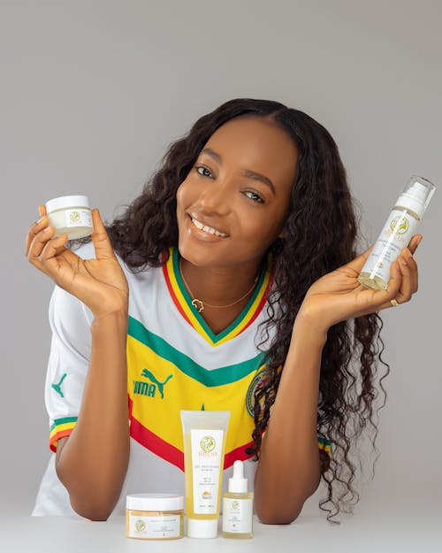 Smiling Woman in Soccer Jersey Holding Cosmetics