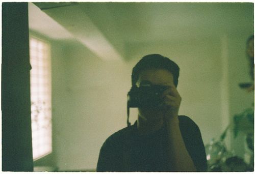 Free Silhouette of a person capturing a mirror selfie with a camera in a dimly lit room. Stock Photo