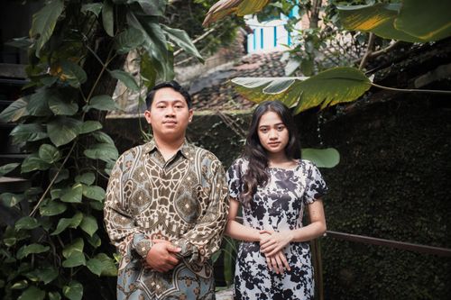 Free A married couple poses elegantly in a lush garden setting, surrounded by vibrant green foliage. Stock Photo