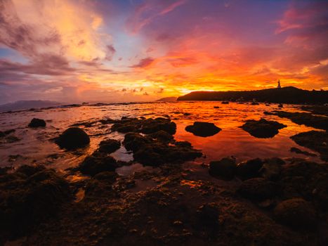 Stunning sunset over a rocky coastline with vibrant sky reflections on the water.