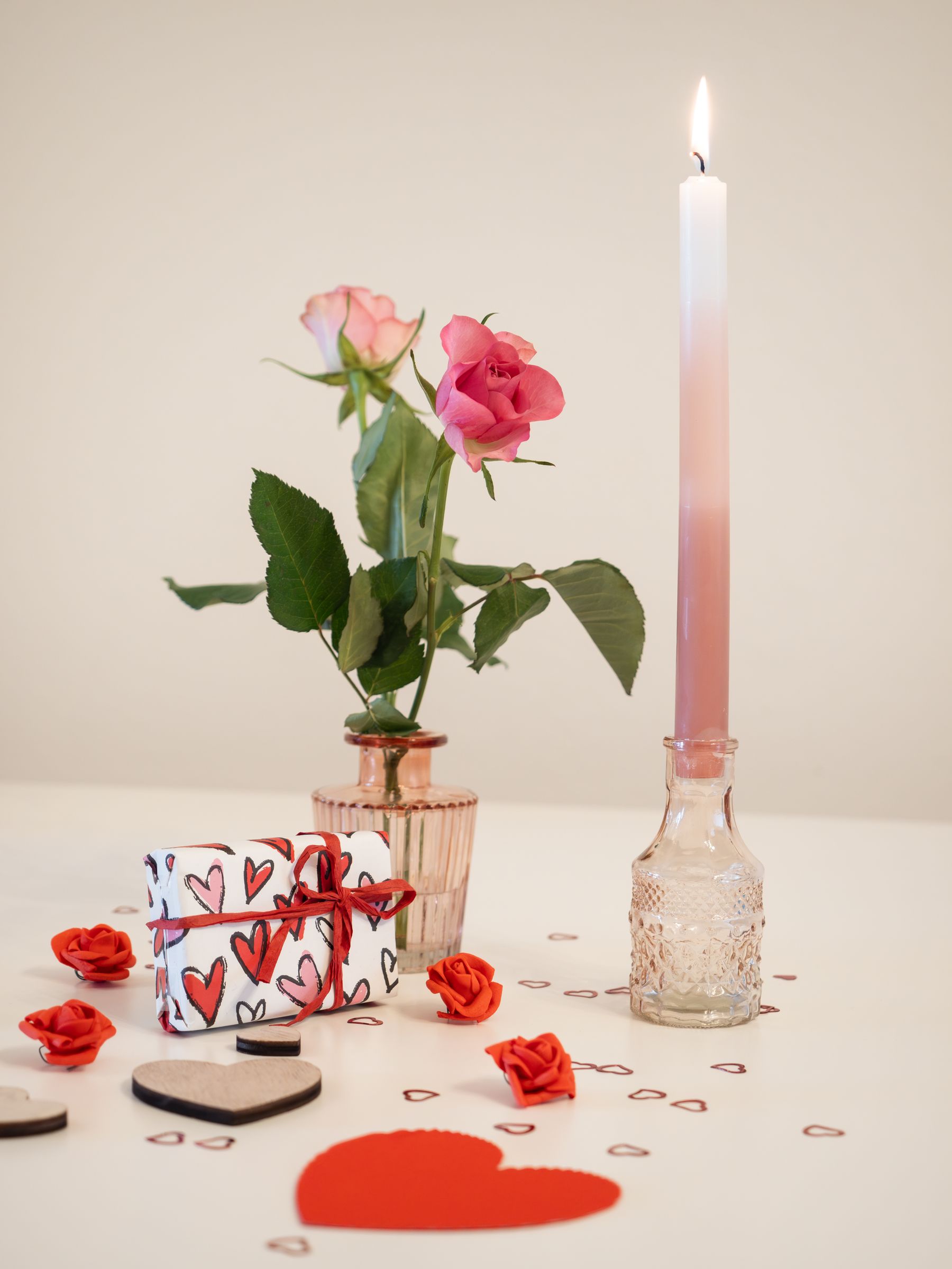 Pink roses, candle and small heart decoration arranged for Valentine's Day