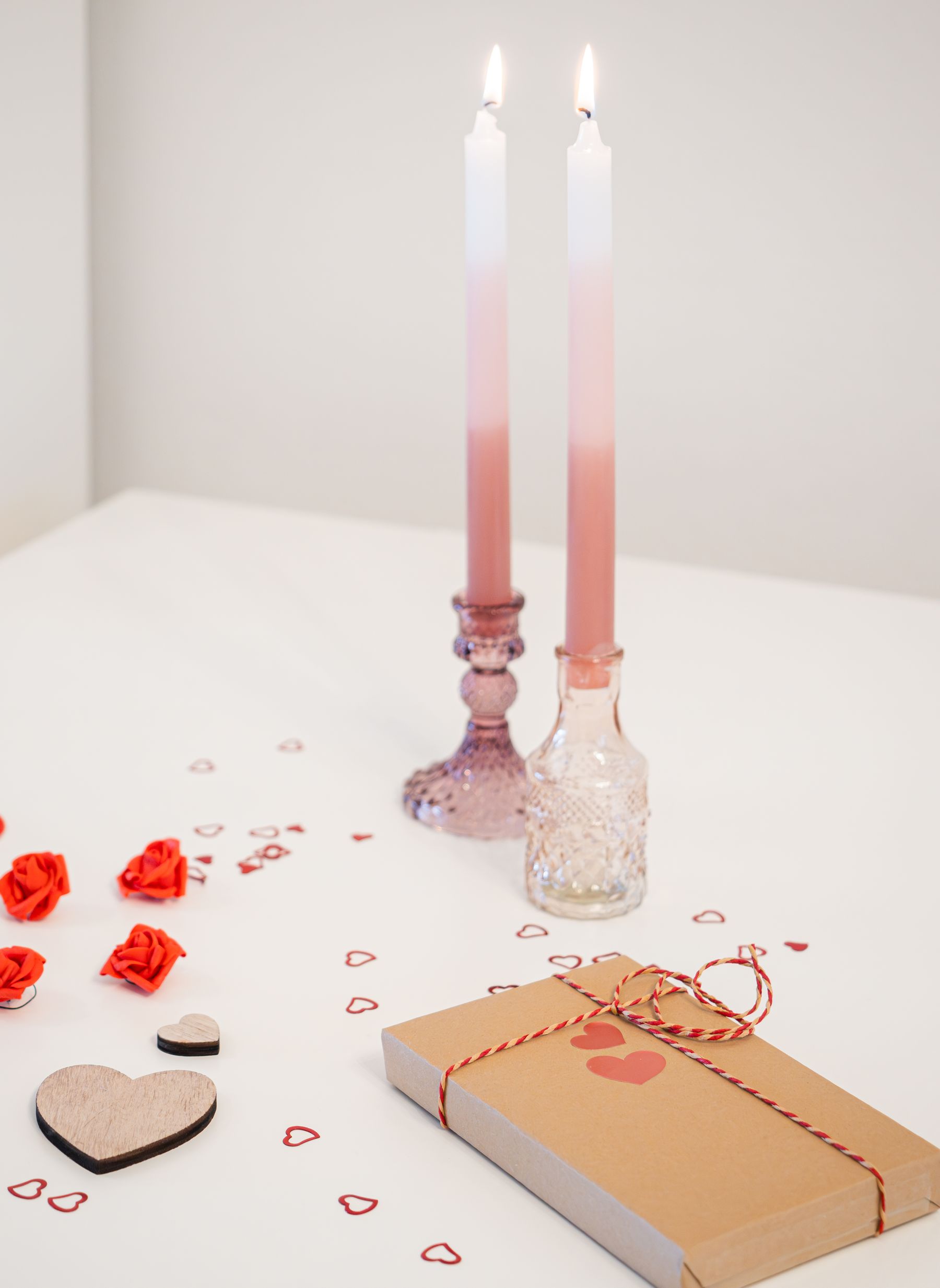 Romantic table vignette with gift, flowers, candles and heart decorations