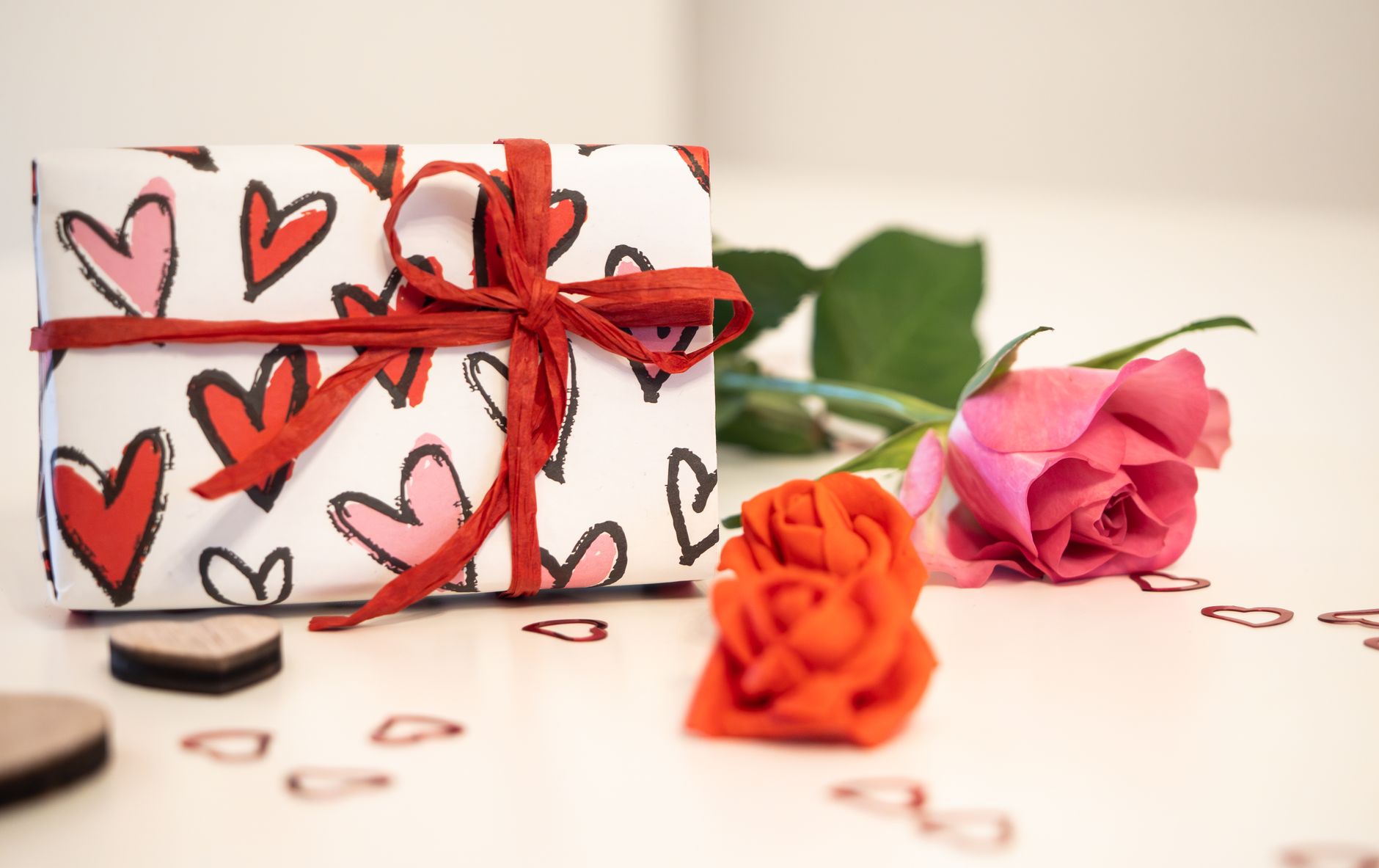 A beautifully wrapped gift adorned with roses and heart decorations, perfect for romantic occasions.