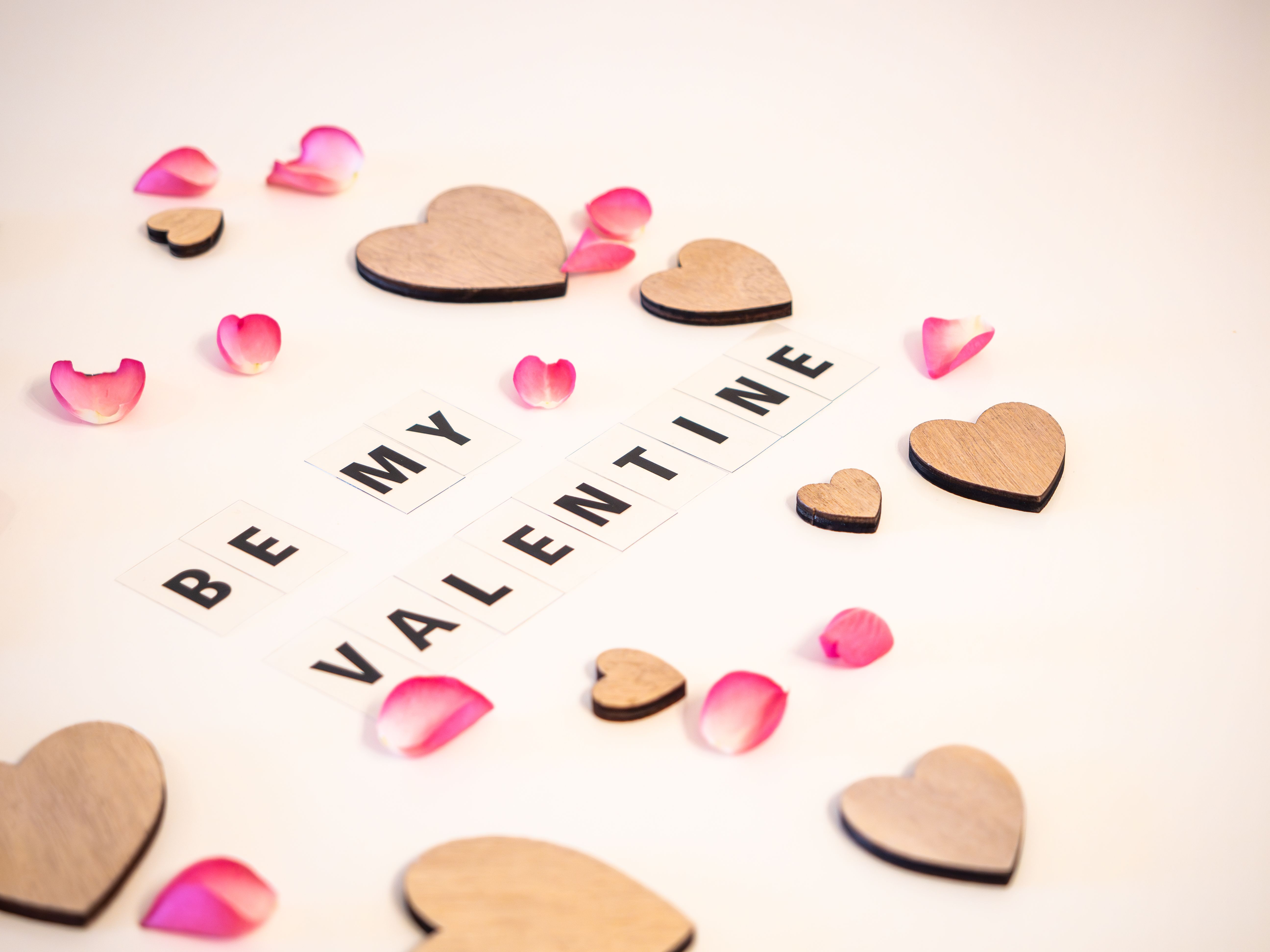 Heartfelt arrangement of wooden hearts and petals with 'Be My Valentine' text.