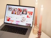 A romantic setup featuring a laptop with Valentine's posts and pink candles, perfect for a cozy atmosphere.