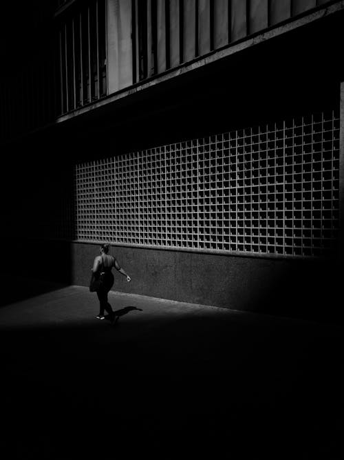 Woman Walking near Building in Black and White