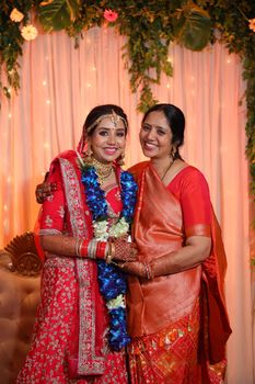 Bride and bridesmaid in vibrant traditional attire at an Indian wedding.