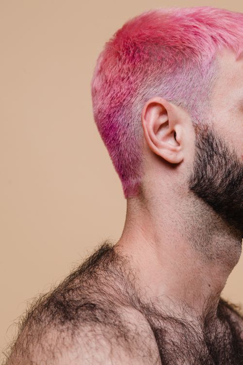 Free A striking portrait of a man with pink hair and a beard, emphasizing unique style and body hair. Stock Photo