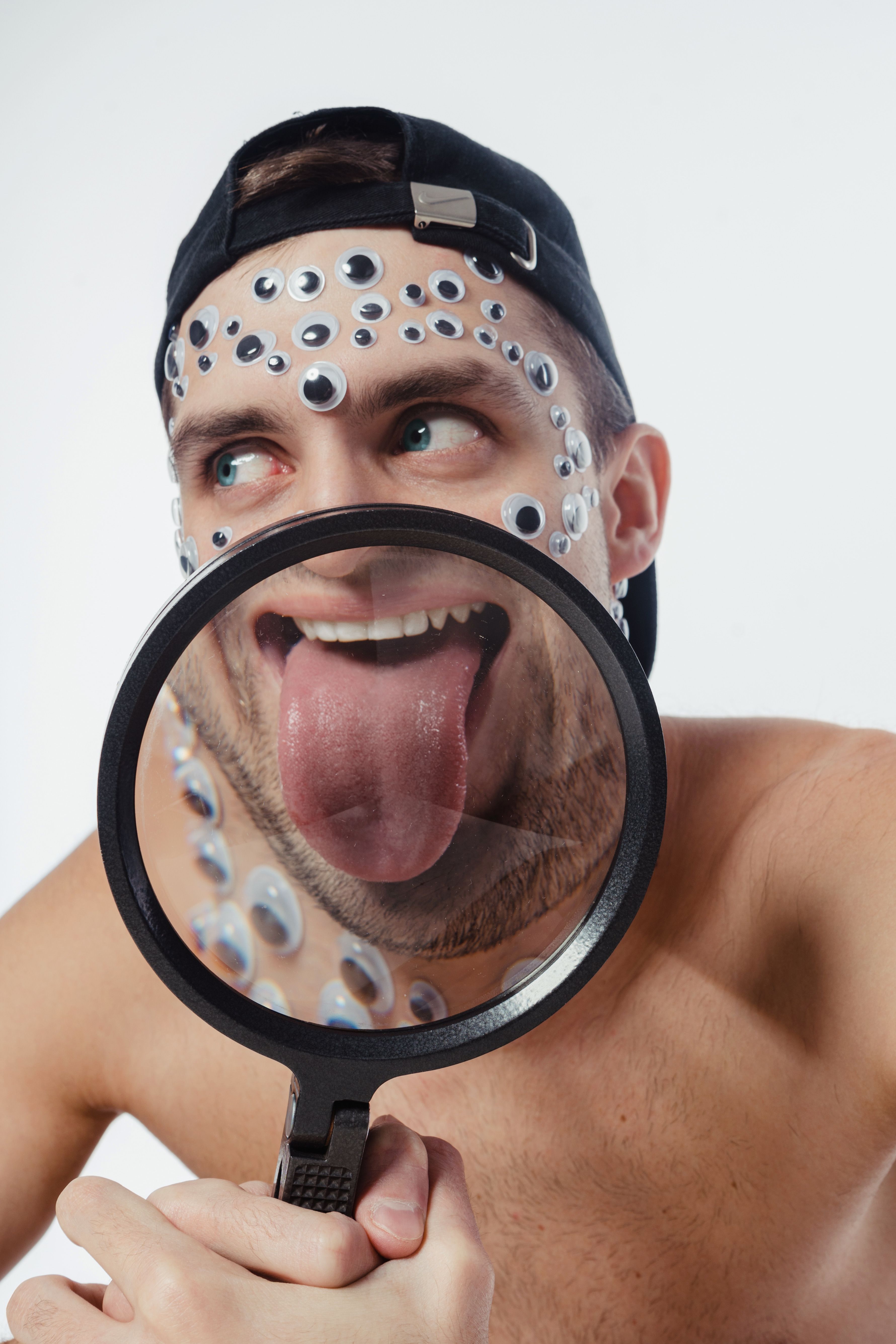 Playful image of a man with googly eyes and a magnified tongue in a studio setting.