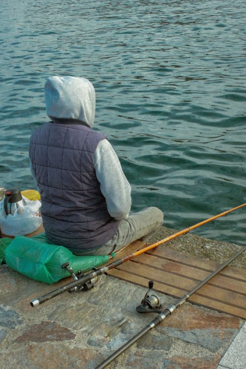 Angler is Sitting on Promenade with Two Rods