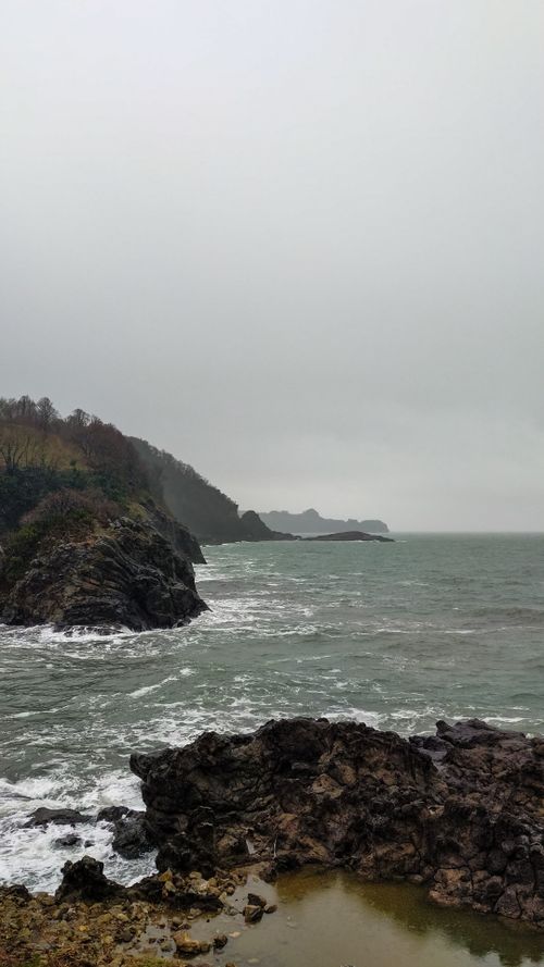 Free A dramatic view of a rocky coastline and sea waves under overcast skies. Stock Photo