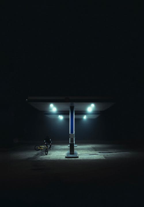 Man Doing Stunts on Bike at Gas Station at Night