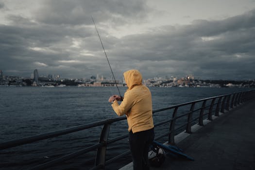 A man fishing at dawn on the Bosphorus in Istanbul, capturing the moody atmosphere and cityscape.