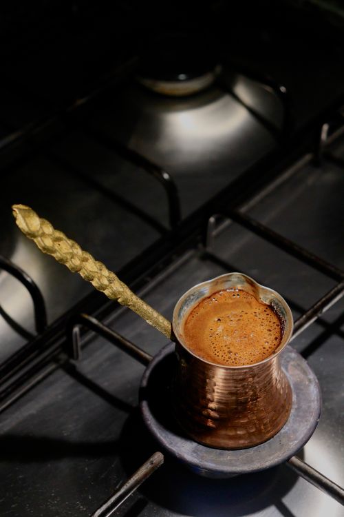 Free A copper coffee pot brewing Turkish coffee on a stovetop. Rich foam forming. Stock Photo