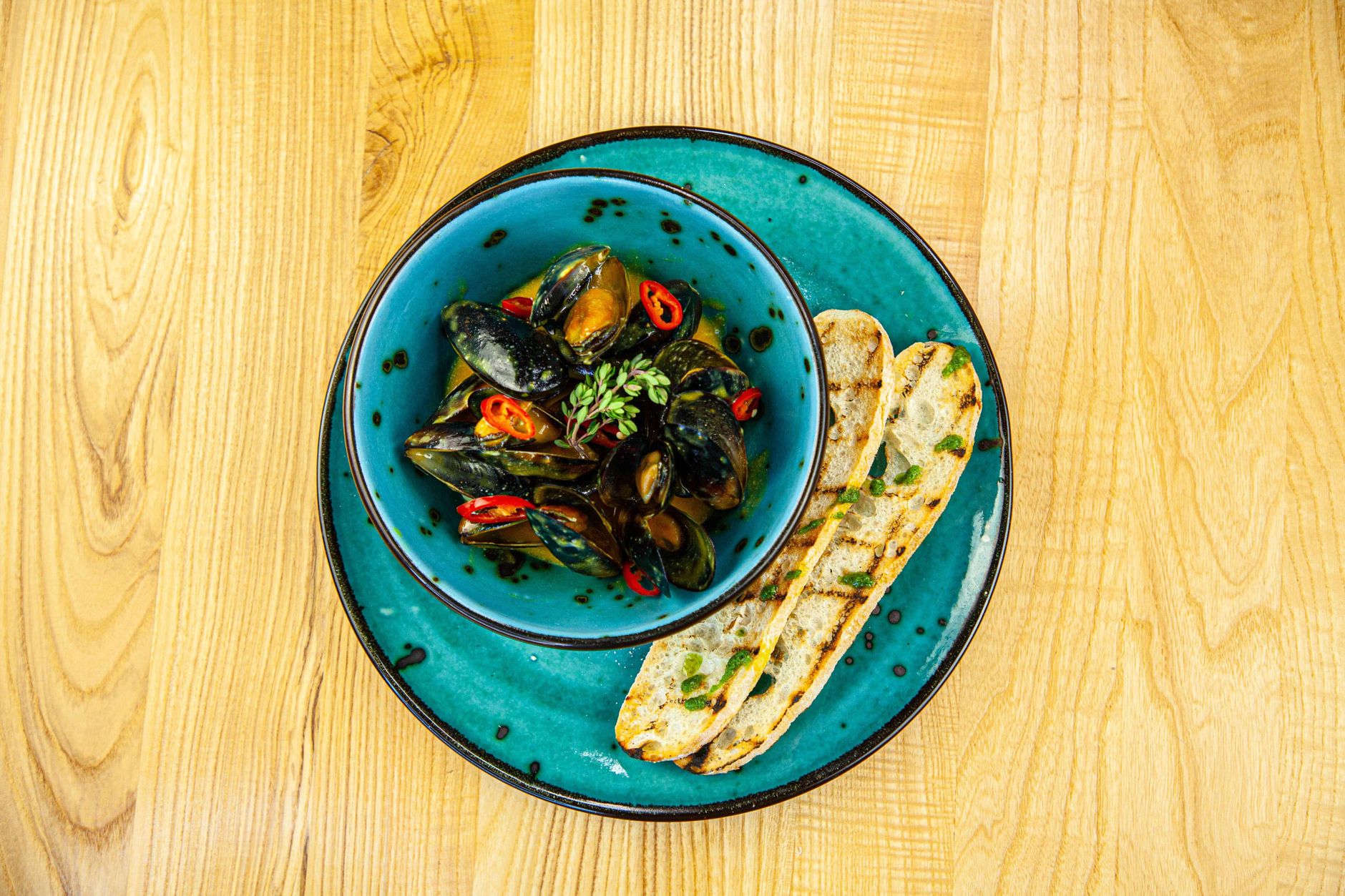 Plate of grilled sardines and bread on a tiled restaurant table