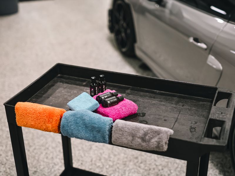 Professional detailing products and microfibre towels on a workshop cart
