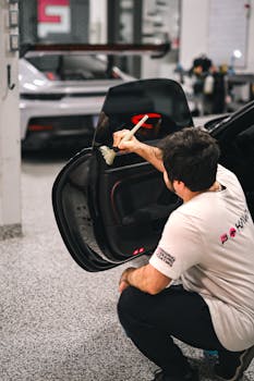 A mechanic meticulously cleaning a car door in a professional workshop setting, showcasing care and precision.