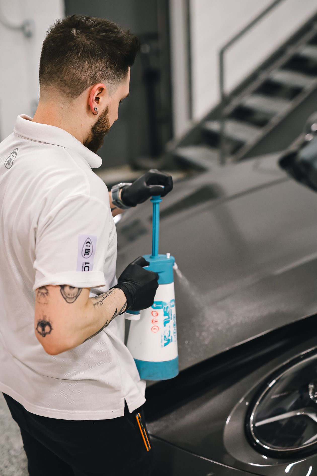 Detailer misting product onto a bonnet before polishing