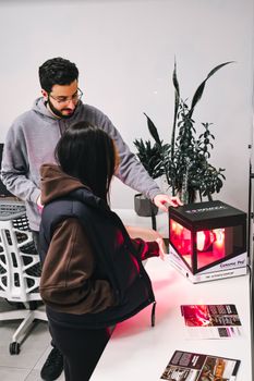 A man and woman exploring a modern lighting display in a bright indoor setting.
