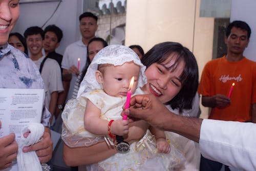 Free A baby being held by a woman with a candle Stock Photo