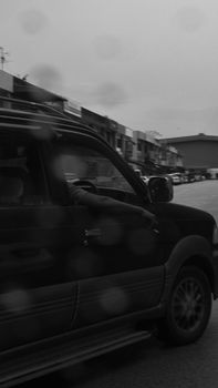 A black and white photo capturing a car and city street with a moody atmosphere.