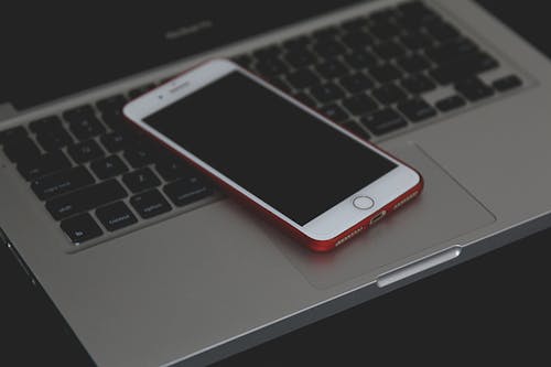 Free Shallow Focus Photo of Silver Iphone 6 on Gray Laptop Computer Stock Photo