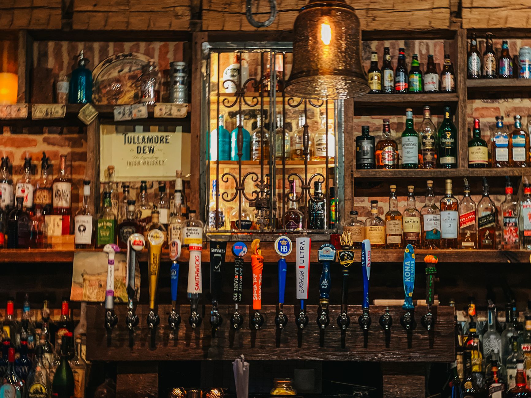 A row of craft beer taps on a polished bar with a chalkboard menu behind