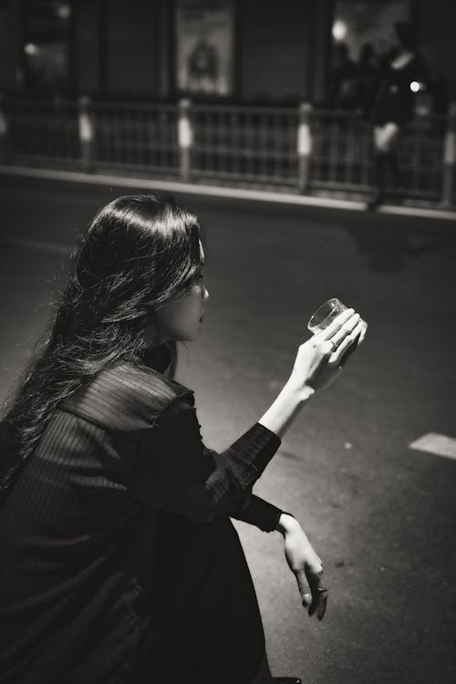 Woman Drinking on Street at Night