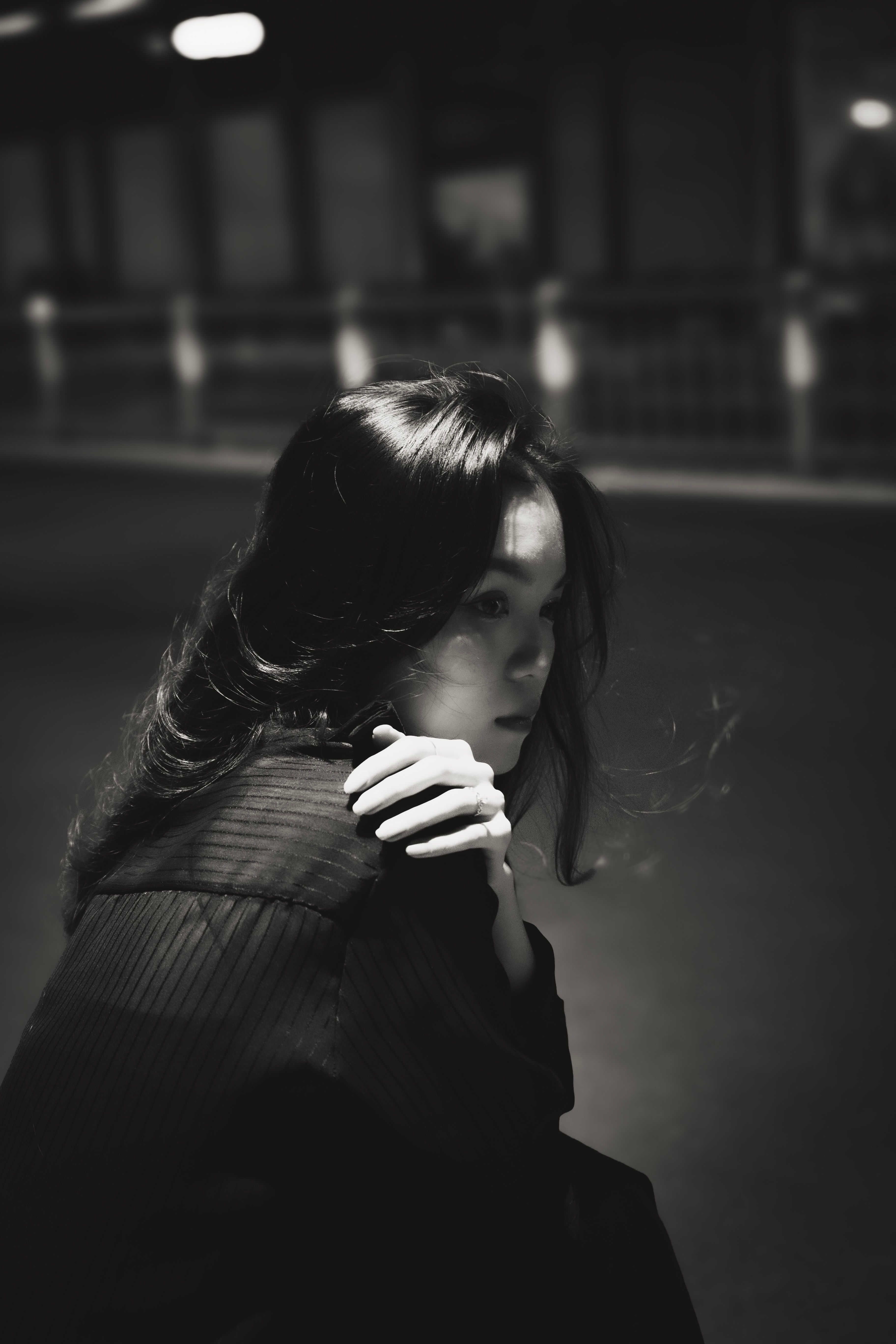 Woman Sitting with Hand on Shoulder in Black and White · Free Stock Photo