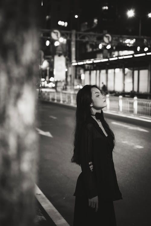 Woman Standing with Eyes Closed on Street in Black and White