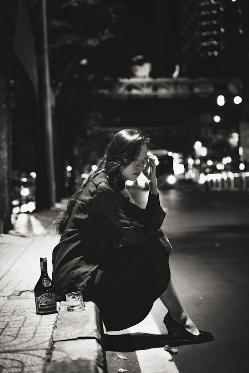Woman Sitting with Bottle and Glass by Street