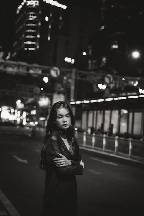 Woman Standing with Arms Crossed on Street at Night