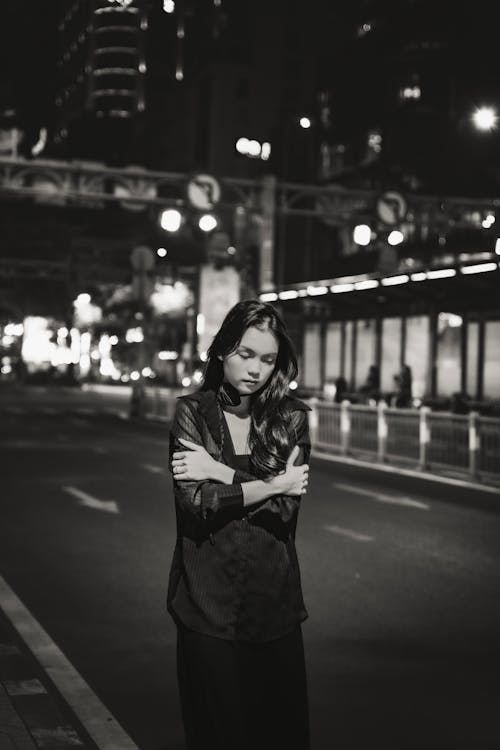 Woman Standing with Arms Crossed and Looking Down on Street