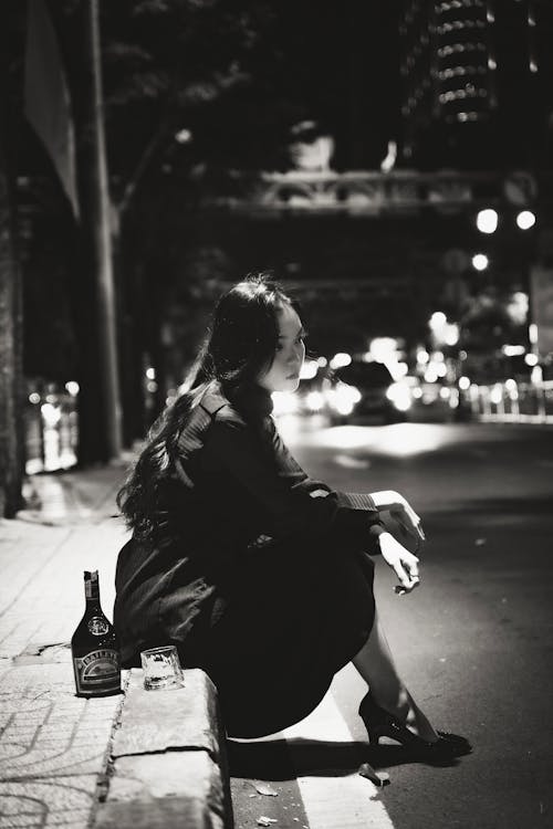 Woman Sitting with Bottle and Glass by Street