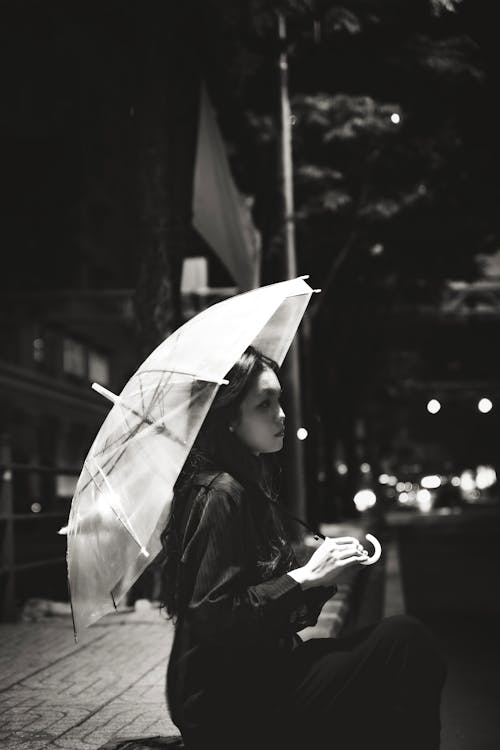 Woman Sitting with Umbrella at Night