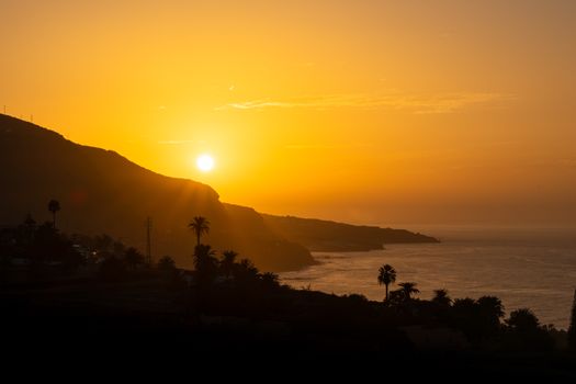 Breathtaking sunset view in Garachico, Spain with silhouetted coastline and vibrant sky.
