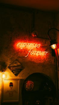 A dimly lit coffee shop featuring a glowing red neon sign that reads 'espresso forever'.