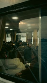 Passengers seated inside a ferry at night, enjoying a warm ambiance as they travel across waters.