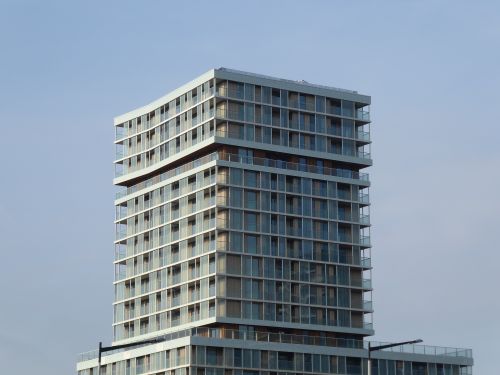Free Contemporary high-rise building with glass facade under clear blue sky. Stock Photo