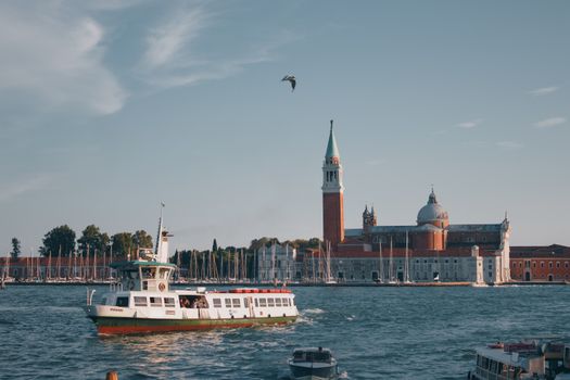 Scenic view of San Giorgio Maggiore with boats on the Grand Canal in Venice, Italy, under a clear summer sky.
