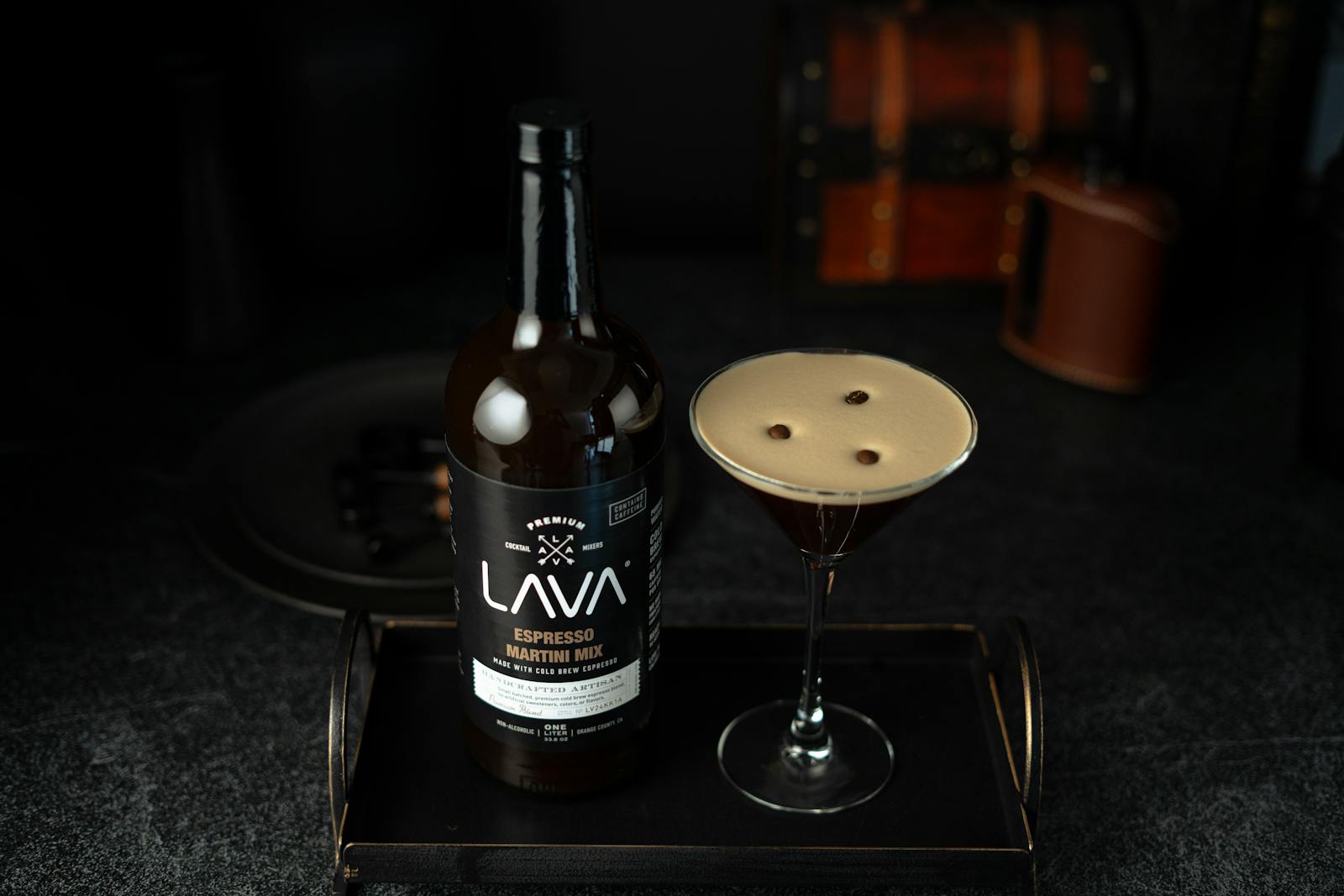 Espresso martini and bottle on a dark serving tray