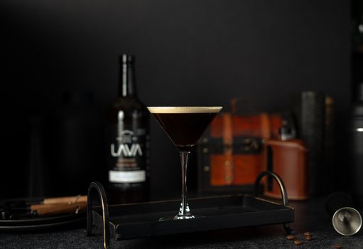 A sophisticated espresso martini served on a stylish tray against a black backdrop.