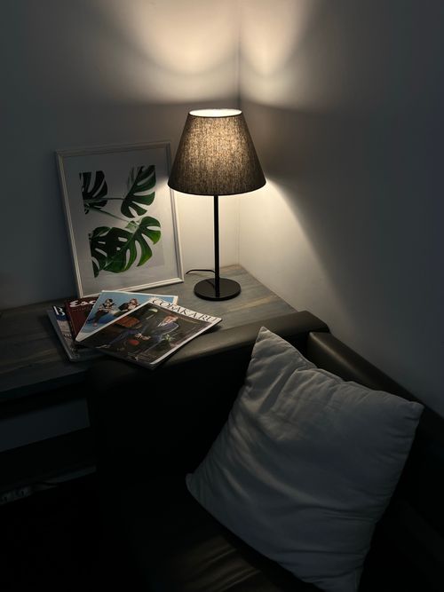 Free A serene corner featuring a lamp, decorative frame, and magazines, ideal for a cozy reading setting. Stock Photo