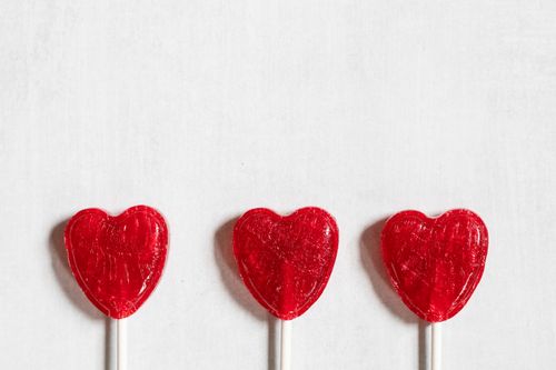 Free Three red heart-shaped lollipops arranged against a white background, offering a sweet and romantic theme. Stock Photo