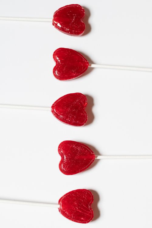Free Five red heart-shaped lollipops arranged on a white surface, perfect for Valentine's Day. Stock Photo
