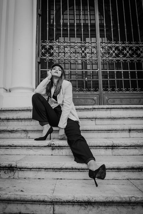 Woman Wearing a Cap Sitting on Stairs in Black and White 
