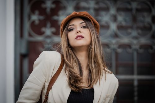 Free A fashionable woman poses confidently in Lisbon, wearing a brown hat and stylish outfit, exuding elegance. Stock Photo