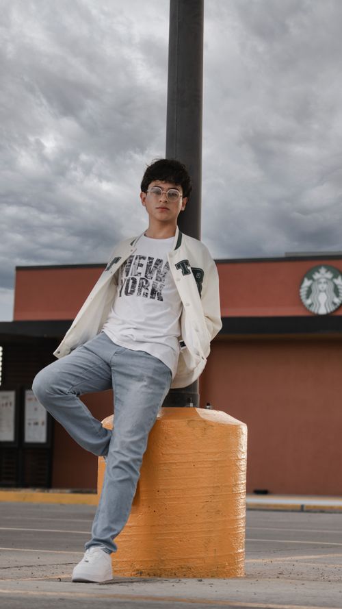 Free Young man poses casually in an urban setting, wearing trendy glasses and casual fashion. Stock Photo