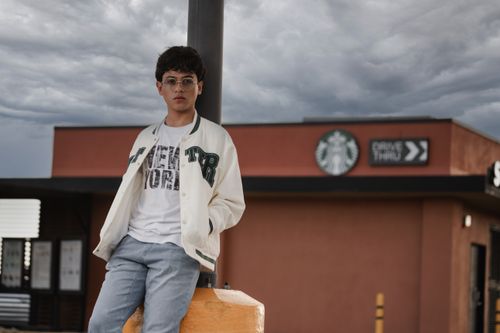 Free Casual portrait of a young man in glasses posing outdoors near a drive-thru cafe. Stock Photo