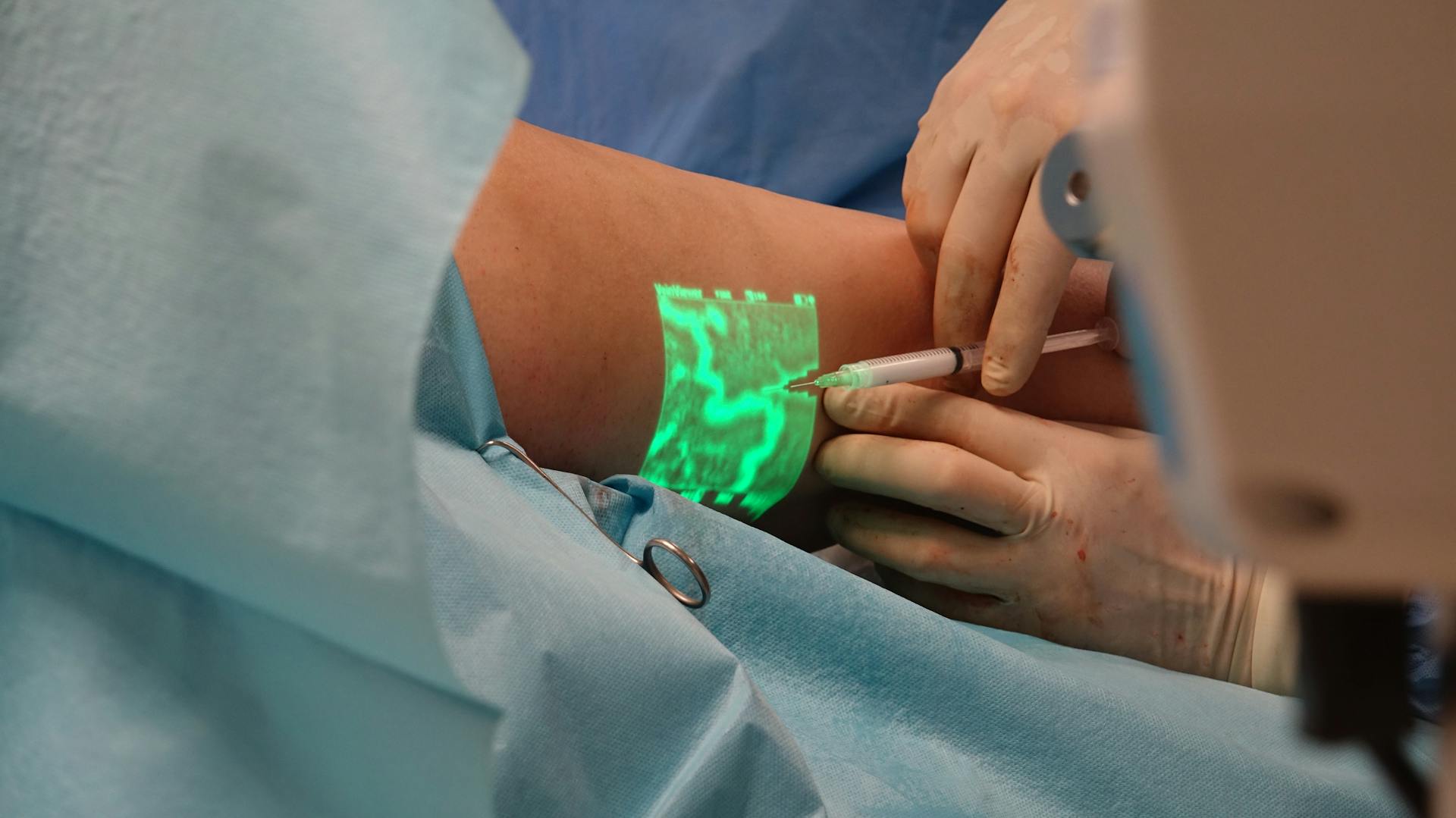 A doctor performs a medical procedure using advanced vein visualization technology.